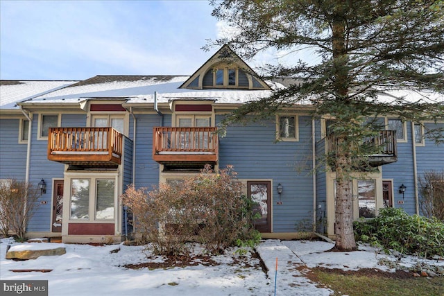 snow covered back of property with a balcony