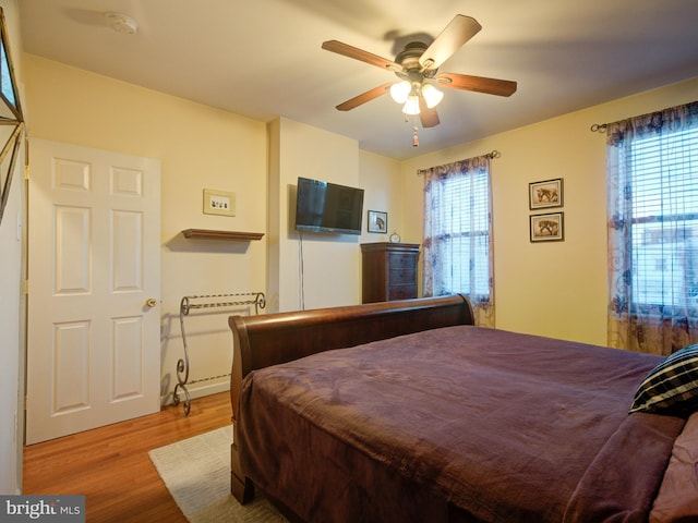 bedroom with ceiling fan, multiple windows, and light hardwood / wood-style flooring