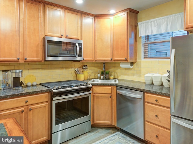 kitchen with tasteful backsplash, appliances with stainless steel finishes, sink, and dark stone counters