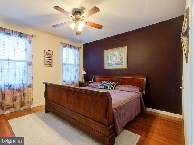 bedroom featuring multiple windows, wood-type flooring, and ceiling fan