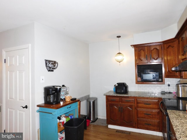 kitchen with electric range, light stone counters, tasteful backsplash, dark hardwood / wood-style flooring, and decorative light fixtures