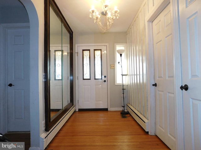 entryway with hardwood / wood-style flooring, a notable chandelier, and a baseboard heating unit