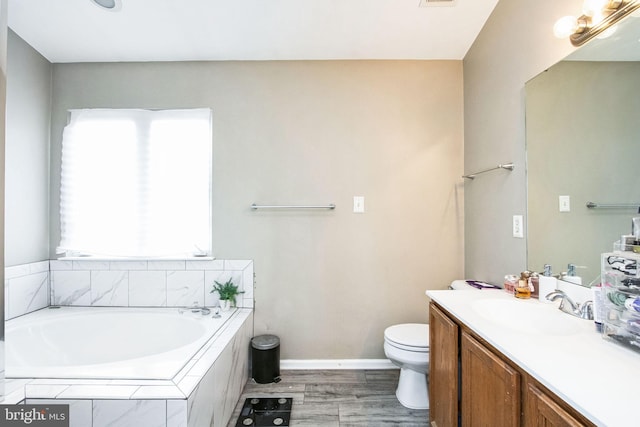 bathroom featuring hardwood / wood-style flooring, vanity, toilet, and tiled tub