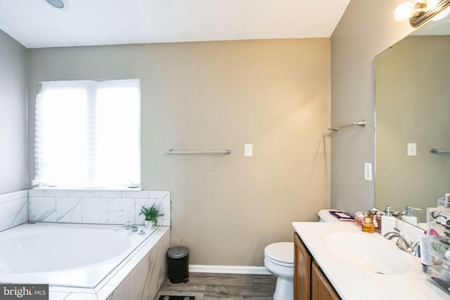 bathroom featuring hardwood / wood-style floors, vanity, a relaxing tiled tub, and toilet