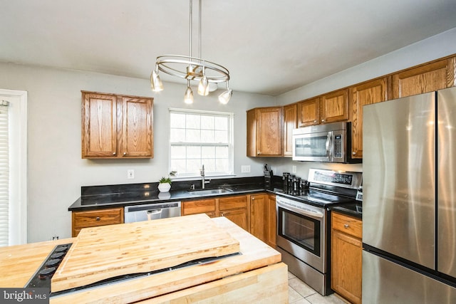 kitchen with light tile patterned flooring, stainless steel appliances, decorative light fixtures, and sink