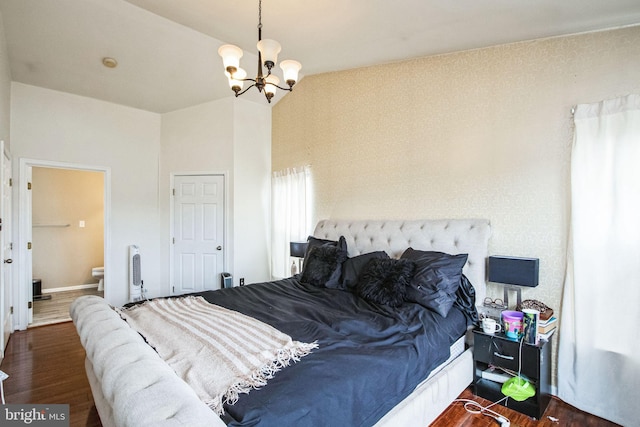 bedroom with ensuite bath, dark hardwood / wood-style flooring, vaulted ceiling, and a notable chandelier