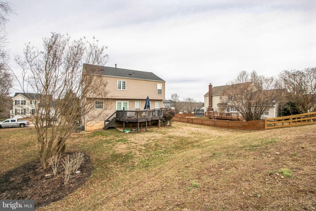 rear view of house featuring a wooden deck and a lawn