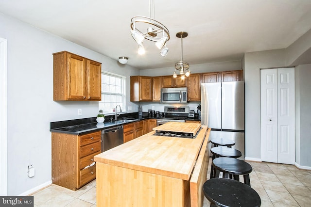 kitchen featuring sink, a center island, light tile patterned floors, appliances with stainless steel finishes, and pendant lighting