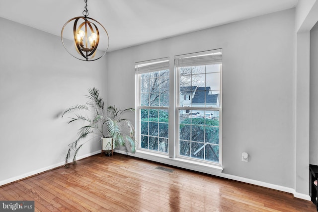 empty room with a chandelier and light hardwood / wood-style flooring