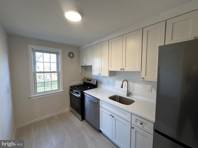 kitchen with tasteful backsplash, appliances with stainless steel finishes, sink, and white cabinets