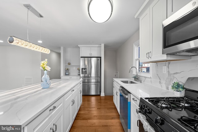 kitchen featuring white cabinetry, stainless steel appliances, sink, and hanging light fixtures