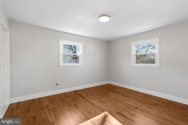 empty room with a healthy amount of sunlight and hardwood / wood-style floors