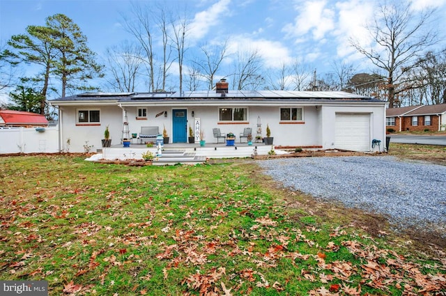 rear view of property with a garage, a lawn, solar panels, and covered porch