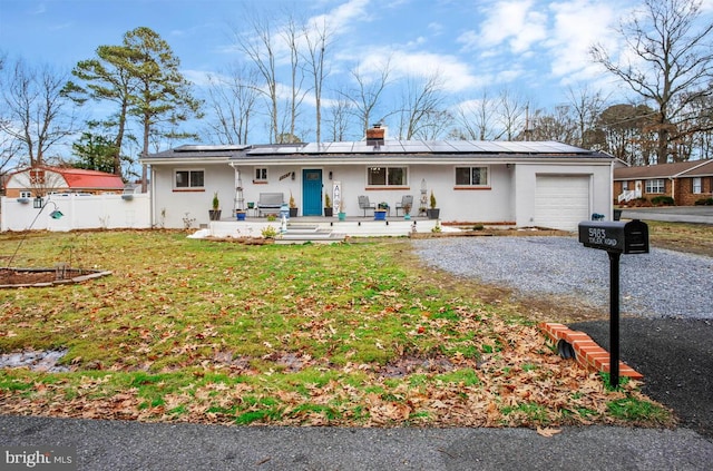 single story home featuring a garage, a front yard, solar panels, and covered porch