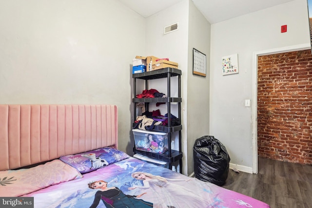 bedroom featuring brick wall, radiator heating unit, and dark hardwood / wood-style floors