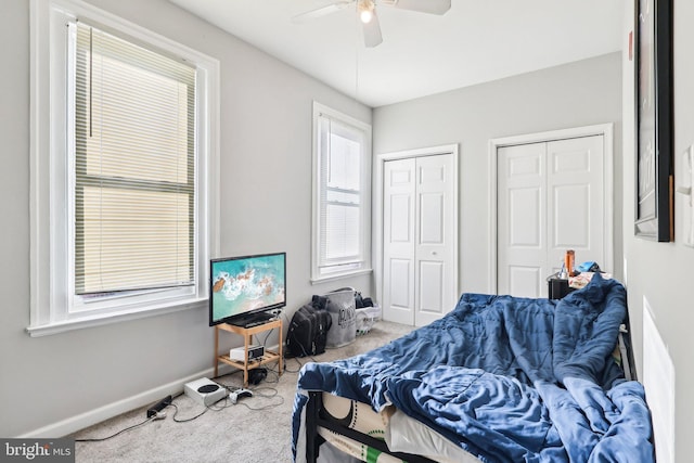 bedroom with ceiling fan, carpet floors, and two closets