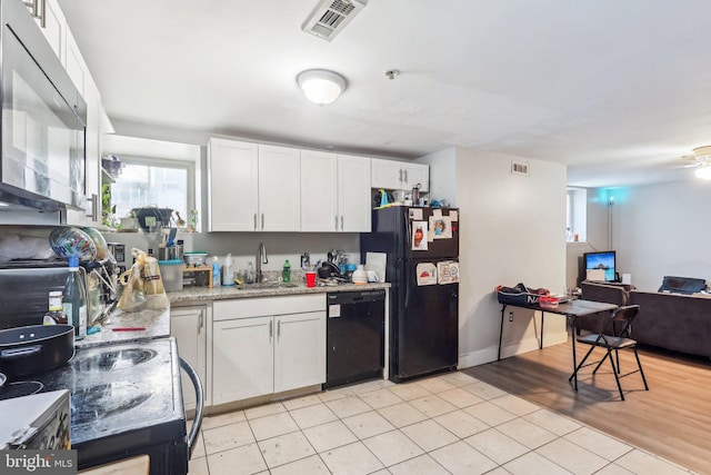 kitchen with white cabinetry, sink, black appliances, light stone countertops, and light hardwood / wood-style flooring