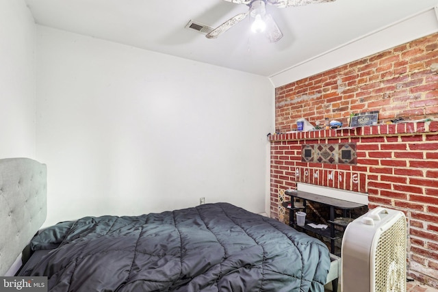 bedroom featuring ceiling fan and brick wall