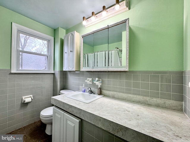 bathroom featuring vanity, toilet, and tile walls