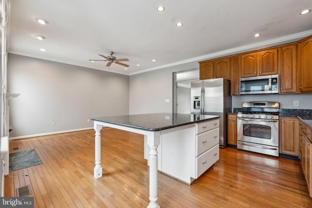 kitchen featuring light wood-type flooring, ornamental molding, and stainless steel appliances