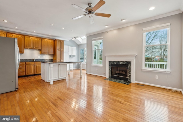 kitchen featuring dark countertops, ornamental molding, open floor plan, freestanding refrigerator, and light wood-type flooring