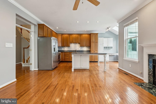 kitchen featuring a premium fireplace, a sink, appliances with stainless steel finishes, light wood finished floors, and dark countertops