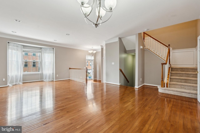 unfurnished living room with a chandelier, ornamental molding, light wood-style flooring, and baseboards