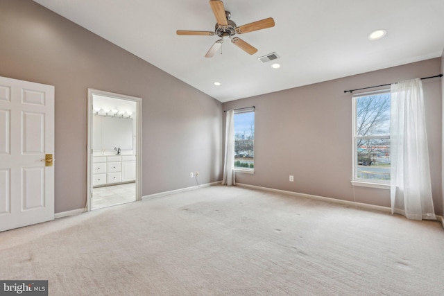 unfurnished bedroom with lofted ceiling, light colored carpet, visible vents, and multiple windows