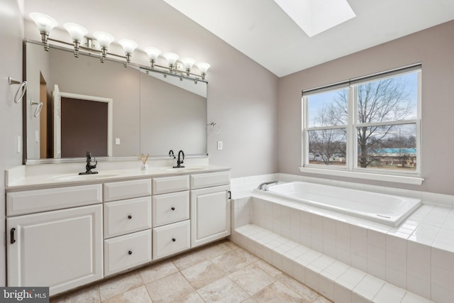 full bath with a garden tub, double vanity, lofted ceiling with skylight, and a sink