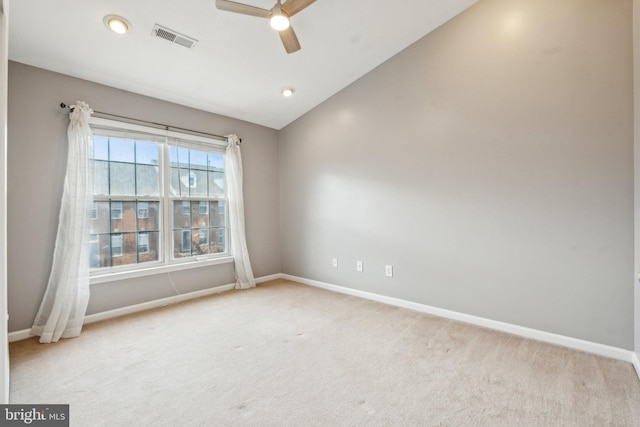 empty room with carpet, visible vents, a ceiling fan, vaulted ceiling, and baseboards