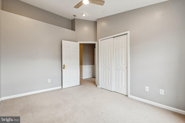 unfurnished bedroom featuring a ceiling fan, a closet, light carpet, and baseboards