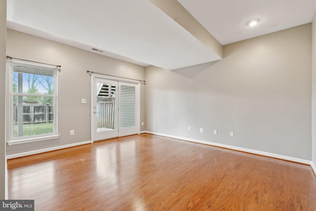 empty room featuring visible vents, baseboards, and wood finished floors