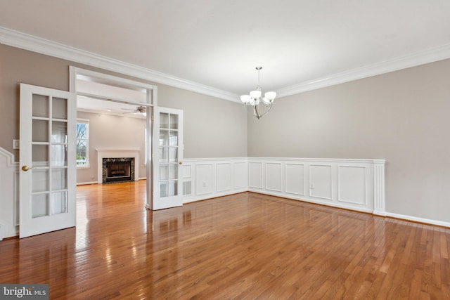 spare room featuring a premium fireplace, ornamental molding, hardwood / wood-style floors, and french doors