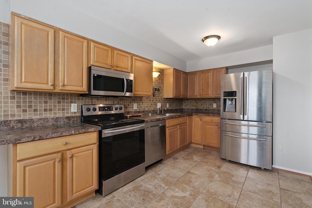 kitchen featuring appliances with stainless steel finishes, sink, dark stone countertops, backsplash, and light tile patterned floors