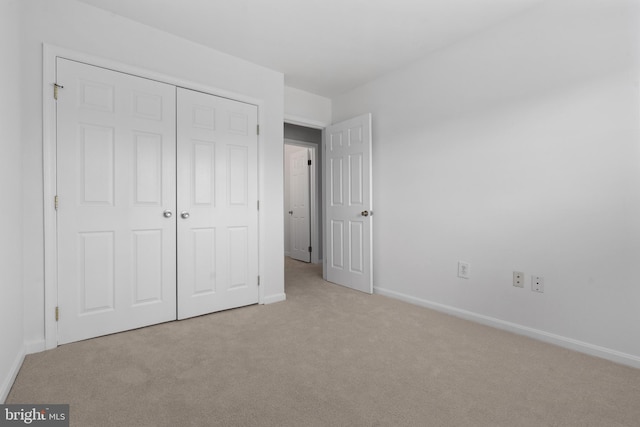 unfurnished bedroom featuring light carpet and a closet