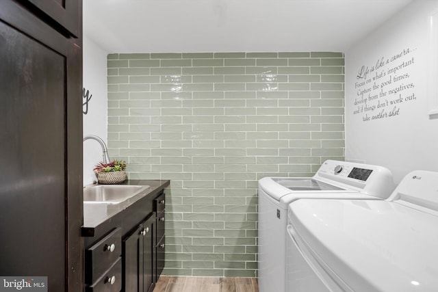 clothes washing area featuring cabinets, independent washer and dryer, sink, and tile walls