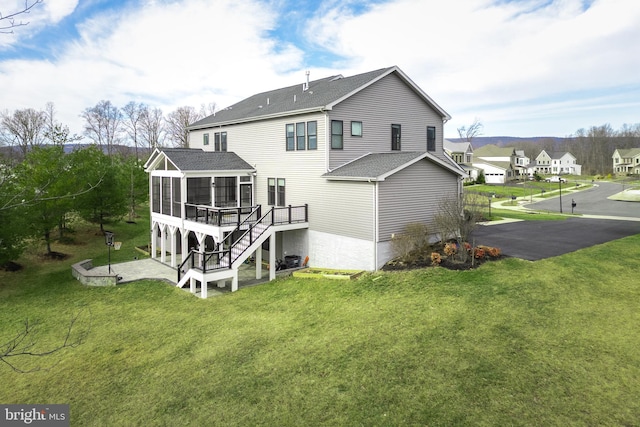 back of property with a patio area, a lawn, a sunroom, and a deck