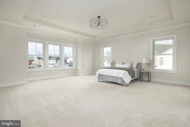 bedroom with multiple windows, light carpet, and a raised ceiling