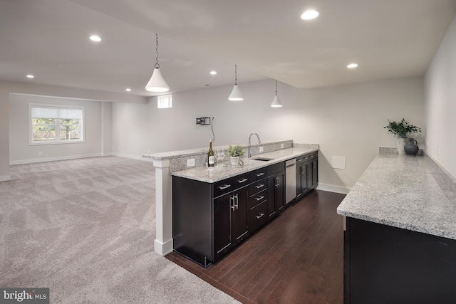 kitchen with pendant lighting, sink, light stone countertops, and dishwasher