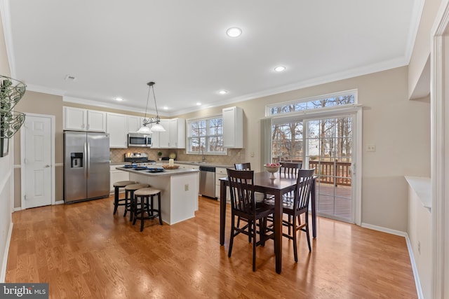 dining space featuring ornamental molding, sink, and light hardwood / wood-style floors