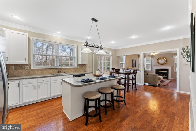 kitchen with light stone countertops, a kitchen island, white cabinets, and decorative light fixtures