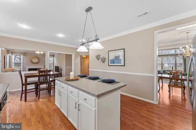 kitchen with a center island, hanging light fixtures, light wood-type flooring, a notable chandelier, and white cabinets