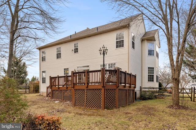 back of property featuring a deck and a lawn