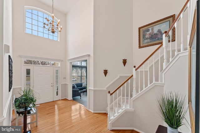 entrance foyer with a notable chandelier, a towering ceiling, hardwood / wood-style floors, and a wealth of natural light