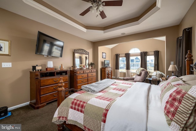 bedroom featuring dark colored carpet, ceiling fan, and a tray ceiling