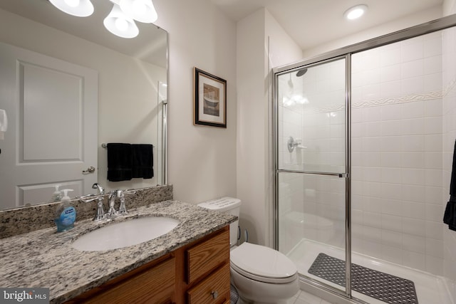 bathroom with vanity, toilet, and a shower with door