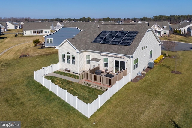 back of house with central air condition unit, a lawn, and solar panels