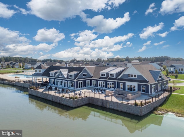 back of house with a water view and a patio