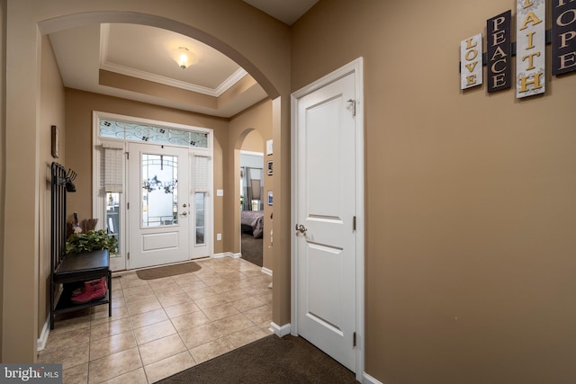 foyer entrance featuring crown molding, light tile patterned flooring, and a tray ceiling