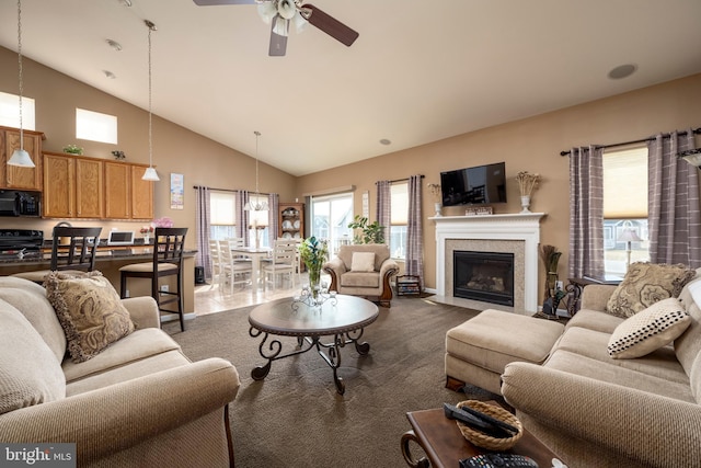 carpeted living room with ceiling fan and high vaulted ceiling